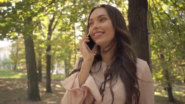 Νεαρή Γυναίκα Μιλάει Στο Smartphone Στο Πάρκο — Αρχείο Βίντεο