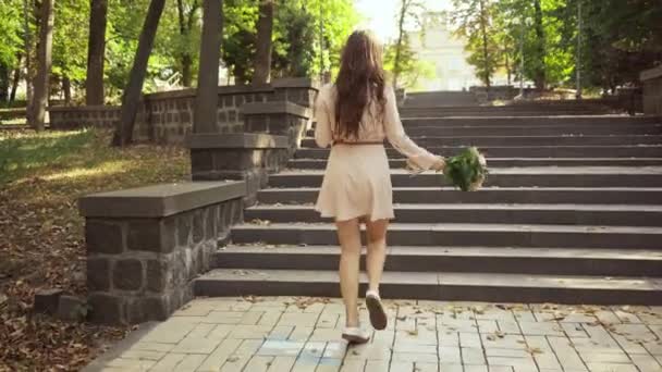 Νεαρή Γυναίκα Μπουκέτο Περπάτημα Και Κάθεται Στις Σκάλες Στο Πάρκο — Αρχείο Βίντεο