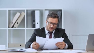 kızgın işadamı kağıtları atma ve akıllı telefon üzerinde konuşma