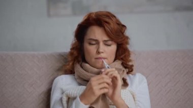 Hasta, üzgün kadın termometreyle ısıyı ölçüyor.
