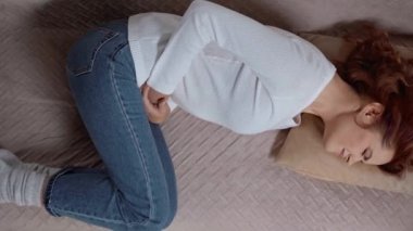 Kanepede yatan ve karın ağrısından muzdarip bir kadın.