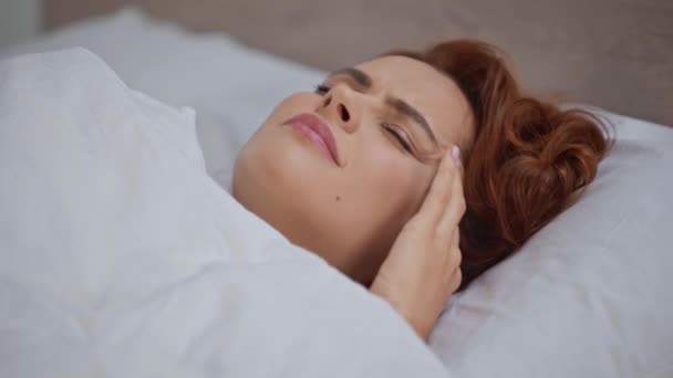 毛布の下に寝そべって頭痛に悩まされる若い女性 — ストック動画