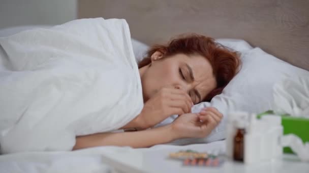 病気の女性がベッドに寝そべってナプキンに咳やくしゃみをして — ストック動画