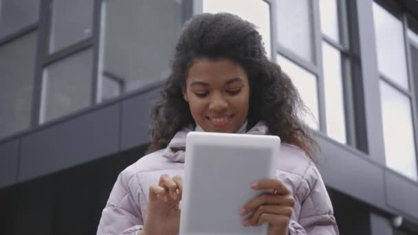 建筑附近使用数码平板电脑的非洲裔美国妇女的低视角照片 — 图库视频影像