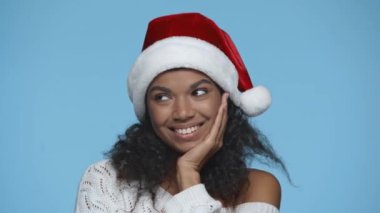 Utangaç gülümseyen Afrikalı Amerikalı kadın Noel Baba şapkalı flört ediyor.