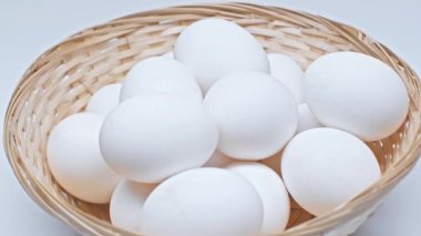 Beyaz yüzeydeki hasır sepette dönen yumurtaların yakın görüntüsü