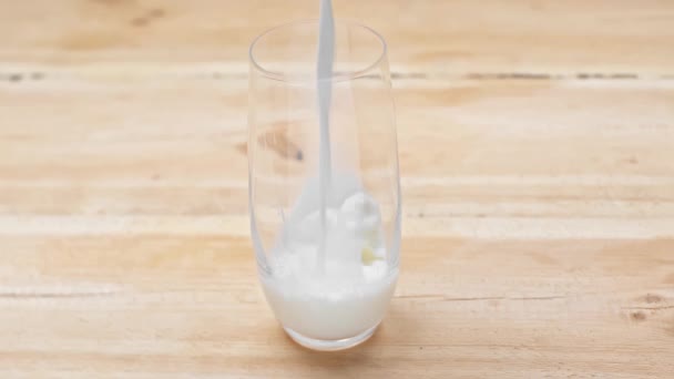 牛奶倒在木制表面的玻璃杯中 — 图库视频影像