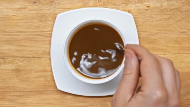 Vue de dessus de l'homme mélangeant café avec cuillère sur la surface en bois 