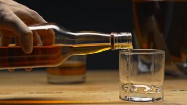 Kırpılmış bir adamın viskiyi siyaha döktüğü görüntüsü.