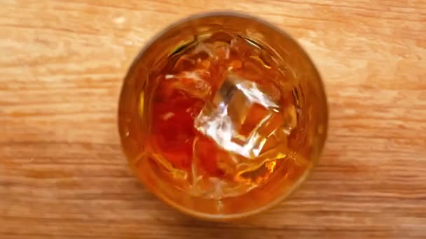 冰块缓缓地掉进木制桌子上的威士忌里 — 图库视频影像