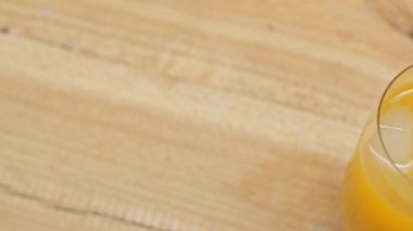 Portakal suyu bardağında buzun üst görüntüsü ve ahşap yüzeyde portakallar.