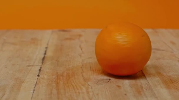 オレンジに隔離された木製の表面にオレンジを回転させる動きが遅い — ストック動画