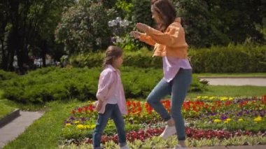 Duygusal anne ve kızı dışarıda çiçek tarlasının yanında tepiniyorlar. 