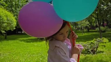 Parkta renkli balonlarla koşan sevimli çocuk. 