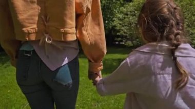 Güzel kız ve anne parkta yürürken el ele tutuşuyorlar. 