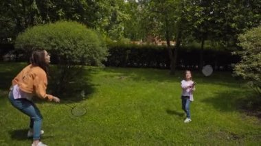 Anne ve kızı parkta badminton oynuyorlar. 