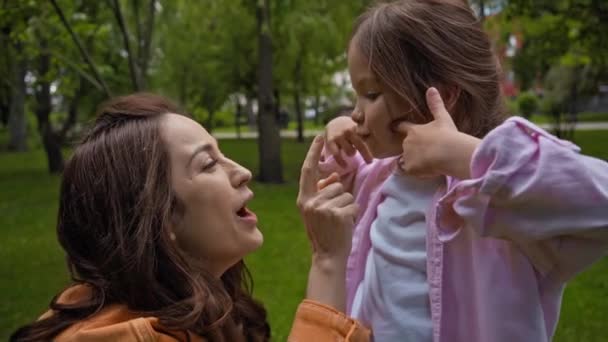幸せなお母さんはかわいい娘の鼻に触れる外 — ストック動画