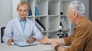 Orta yaşlı doktor insan üzerinde pirometre kullanıyor ve tanı koyuyor 