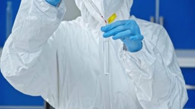 Bilim adamı test tüpüne laptopun yanındaki sıvıyla örnek ekliyor 