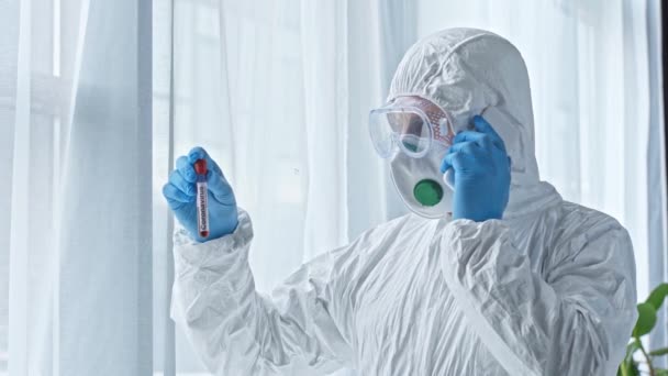 Επιστήμονας Στολή Hazmat Μιλάει Στο Smartphone Και Ψάχνει Δοκιμαστικό Σωλήνα — Αρχείο Βίντεο