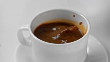 Yavaş çekimde, beyaz üzerine izole kahve dökülen şeker küpleri.