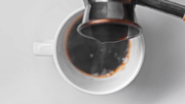 vue du dessus du café versant dans la tasse de la cafetière cezve sur blanc