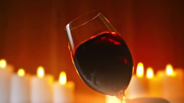 Červené Stříkající Víno Vinném Skle Hořícími Svíčkami Pozadí — Stock video