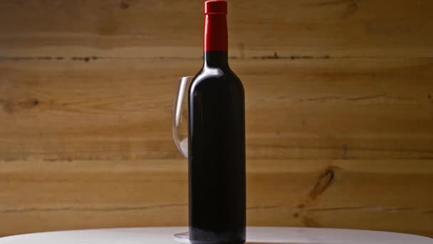 Bottle Red Wine Empty Wineglass Spinning Wooden Background — Stock Video