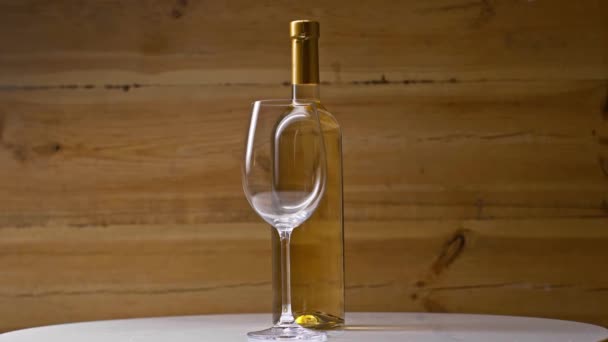 Butelka Białego Wina Pobliżu Pustego Kieliszka Wirującego Drewnianym Tle — Wideo stockowe