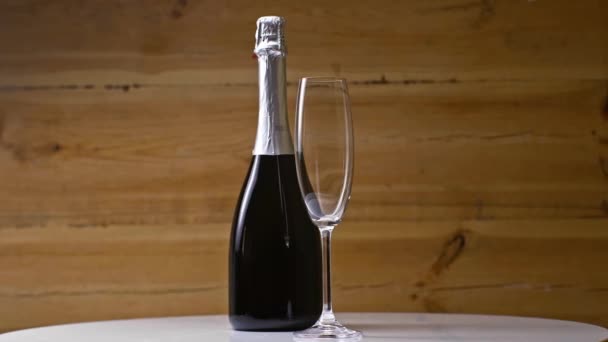 Prázdné Šampaňské Sklo Blízkosti Láhve Točení Dřevěném Pozadí — Stock video