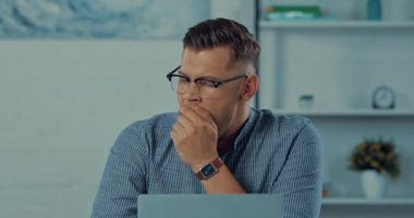 Yorgun serbest çalışan esniyor ve evde gözlüklerini çıkarıyor.