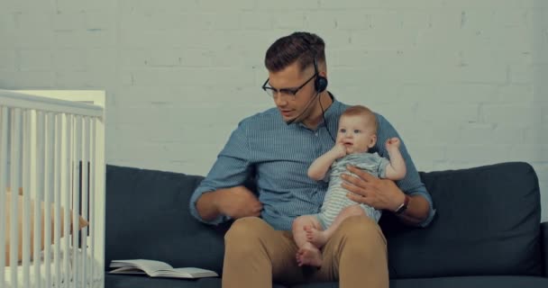 Stilig Operatör Håller Spädbarn Son När Arbetar Hemifrån — Stockvideo