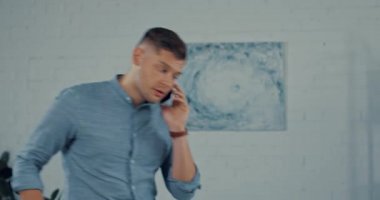 Yakışıklı adam akıllı telefondan konuşuyor ve dijital tablet kullanıyor.