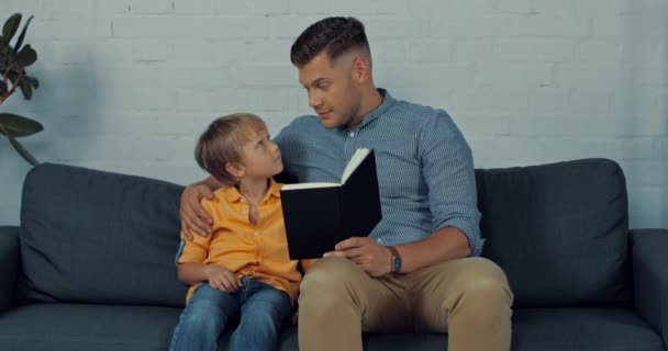 Красивий Батько Читає Книгу Вголос Милому Синові Вдома — стокове відео