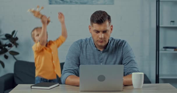 Selective Focus Stressed Man Using Laptop Son Playing Home — Stock Video