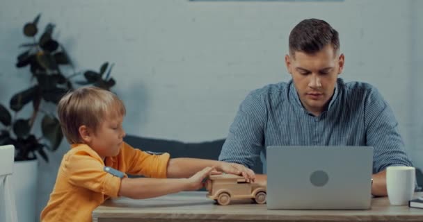 Displeased Father Using Laptop Son Playing Toy Car Home — Stock Video