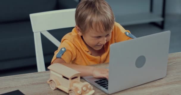 Вибірковий Фокус Веселого Дитини Використовуючи Ноутбук Біля Дерев Яної Іграшки — стокове відео