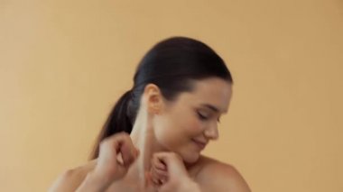 Mükemmel ciltli çıplak bir kadın. Bej rengi elbiseler içinde gülümseyip dans ediyor.