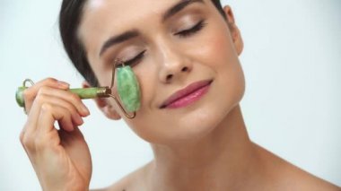 Gri arka planda yeşil silindir kullanan çıplak bir kadın.