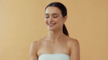 Güzel, gülümseyen bir kadın bej üzerine greyfurt atıyor.