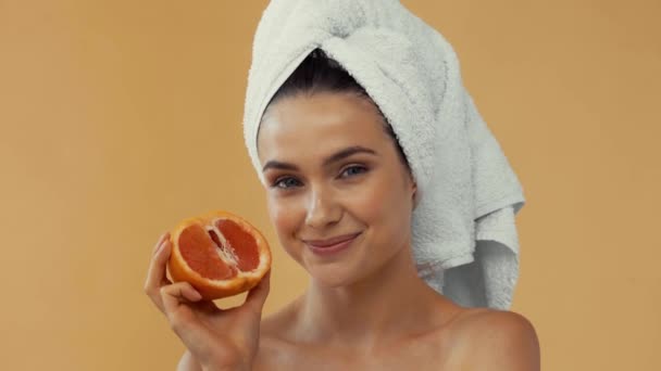 穿着毛巾的裸体女人微笑着 拿着一块用米色隔开的柚子 — 图库视频影像