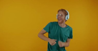 Sarı kulaklıklı mutlu kızıl adam yalnız çalışıyor.