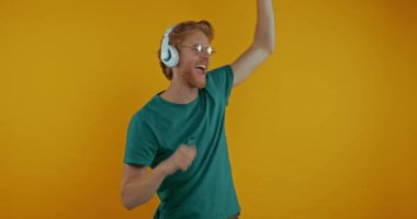 Sarı kulaklıklı mutlu kızıl adam yalnız dans ediyor.