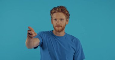 Kızıl saçlı adam parmağıyla işaret ediyor ve mavi üzerine izole edilmiş baş parmağını gösteriyor.