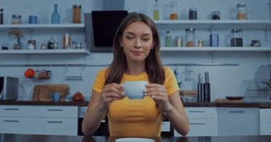 Güzel genç bayan mutfakta kahve içiyor. 