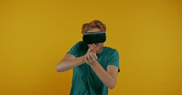 红色头发的男子在Vr耳机玩射击游戏孤立在黄色 — 图库视频影像