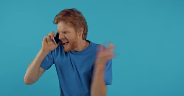 Naštvaný Ryšavý Muž Křičí Smartphonu Izolované Modré — Stock video