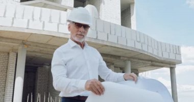 Şantiyede gülümseyen planlı yakışıklı bir mühendis.