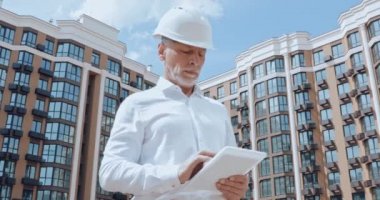 Arkaplanda kentsel caddede binası olan dijital tablet kullanan mühendis