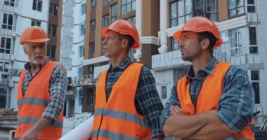 İnşaat alanında yürüyen dijital tabletli ve planlı inşaatçılar